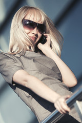 Young fashion business woman talking on mobile phone at office building