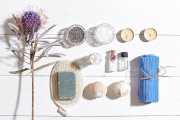 Spa set with sea salt, essential oil, soap and towel decorated with dry flower on white wooden background