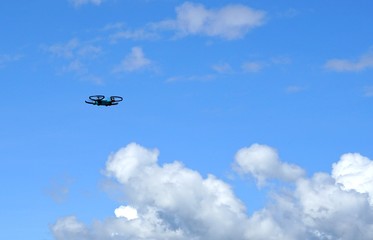 Fototapeta na wymiar Drone ( Unmanned Aerial Vehicle) hovering in blue sky with white clouds background