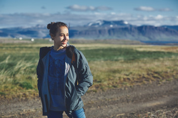 Naklejka na ściany i meble Girl in warm clothing observing surroundings on background of mountains of Iceland.