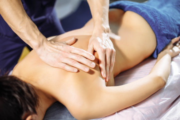 Obraz na płótnie Canvas Closeup of male hands of massage therapist massaging woman's back