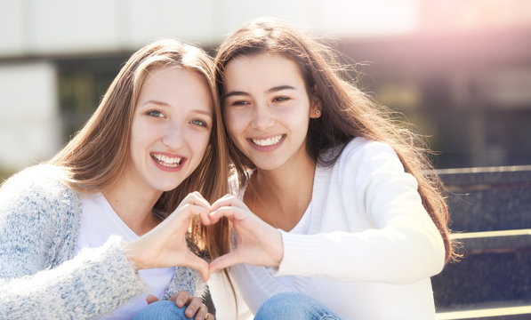 Two Teens Holding Hands in Shape of Heart
