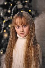 Portrait of a girl on the background of a New Year tree. Festive mood.