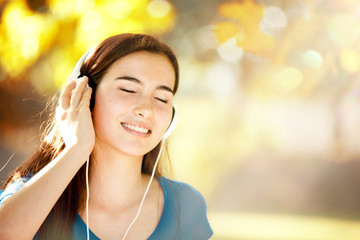Happy Girl Listening to Headphones on a Wonderful Autumn Day