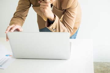 Attractive women in casual business sitting at a table working on her laptop computer at home office in front of a window.
