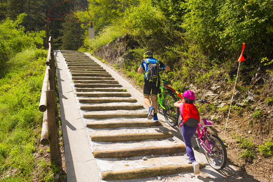 Father and daughter climb the steps with bicycle