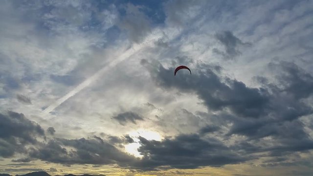 Red paraglider on the background of stormy sky at sunset