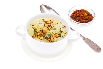Vegetable soup with saffron in white bowl