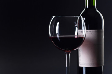 Bottle and glass of red wine .