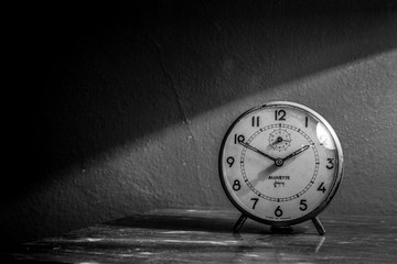 An ancient alarm clock on a table, black and white