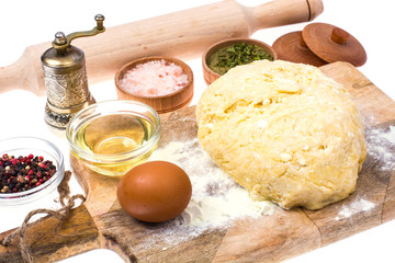 Ball of pizza dough on wooden kitchen cutting board with dusting of flour