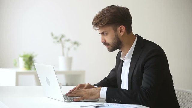 Annoyed angry businessman troubled with sudden computer failure, stressed man having problem with broken pc using laptop, pressing keys on hanging device, leaving workplace unable to fix gadget