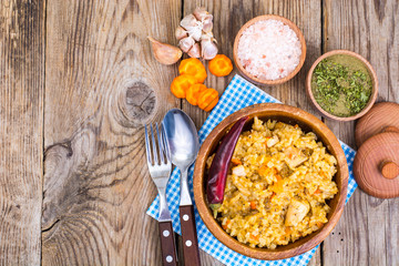 Pilaf with meat and carrots in wooden bowl on the table