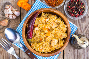 Pilaf with meat and carrots in wooden bowl on the table