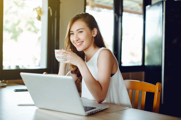 Beautiful Asia woman using laptop and drinking coffee at cafe