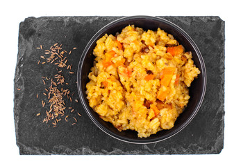 Rice with vegetables in black bowl on white background. View from above