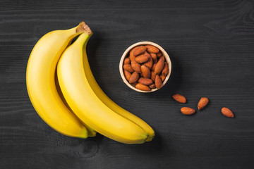 A banch of bananas with almonds on wooden background. © makistock