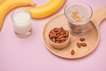 Fresh made banana smoothie in a glass on pink background