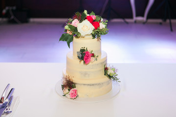 White wedding cake with flowers on table in restaurant
