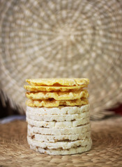 White rice and yellow corn crackers on wicker place mat.