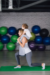 Fototapeta na wymiar Mother and baby girl do exercises together in the gym