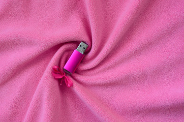 Brilliant pink usb flash memory card with a pink bow lies on a blanket of soft and furry light pink...