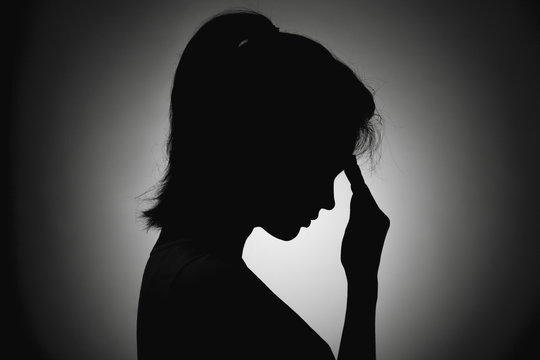 silhouette of the girl face profile of an unrecognizable sad, woman in depression put her hand to forehead