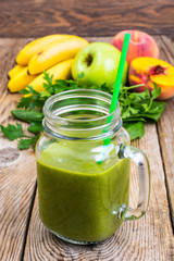 Freshly blended green  smoothie in glass jar on wooden background