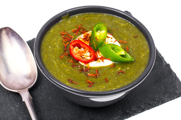 Black plate with spicy cream of spinach soup