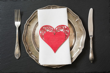 Christmas table setting with vintage dishware, silverware and heart decorations.