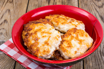 Schnitzels of meat in bowl on wooden table