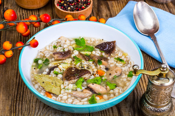 Vegetarian soup with mushrooms and pearl barley for lunch on wooden table