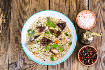 Vegetarian soup with mushrooms and pearl barley for lunch on wooden table