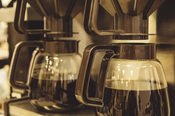 Close-up two coffee brewing machines with jugs and filters.