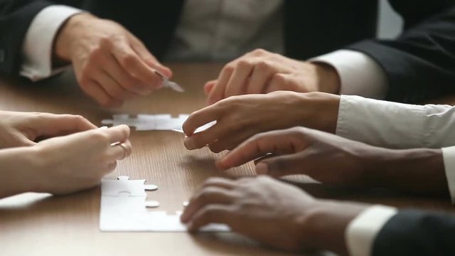 Multiracial business people hands unsuccessfully trying to assemble jigsaw puzzle at office table, team making incorrect decisions, finding wrong solutions in bad teamwork concept, close up view