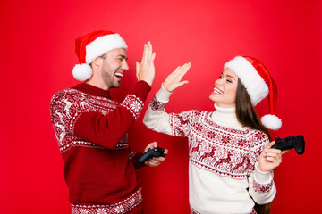 Happiness, winter, chill, december, noel, mode. Excited married couple in traditional x mas head wear are making high five, winning at crazy play station competition, grin and laugh