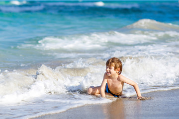 little blond kid boy having fun on ocean beach in Florida