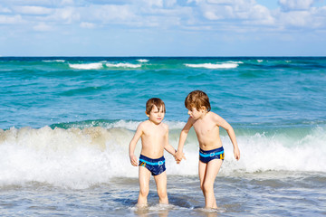 Naklejka premium Two kid boys running on ocean beach in Florida