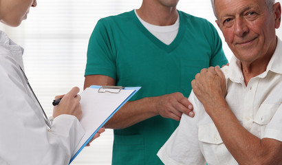 Doctors and senior male patient suffering from back pain during medical exam.