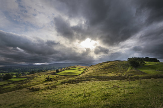 Sun breaks through clouds and shines on rural farmland England