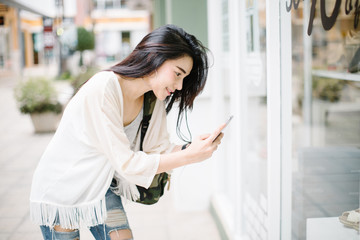 Obraz premium woman walking and using a smart phone in the street in a sunny summer day