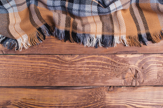 Brown checkered plaid on rustic wooden background.