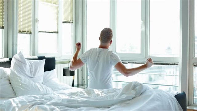 Man stretching in bed, back view