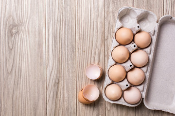Chicken eggs in a cardboard box against the background of a table of wooden boards. Copy space for text