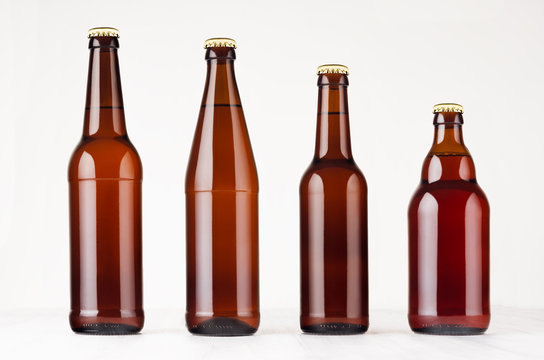 Collection different brown beer bottles, mockup. Template for advertising, design, branding identity on white wood table.