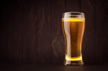 Weizen beer glass with golden sparkling lager on dark wood board, copy space. Template for...
