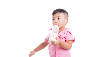 Little asian boy drinking milk from bottle and looking at copy space isolated over white background