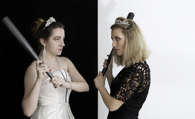Two girls wearing diamond crown and other jewelry fighting with baseball bats. Conflict, competition, and opposition concepts. Isolated on black and white