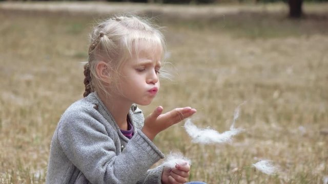 Girl child blowing fluff of bulrush