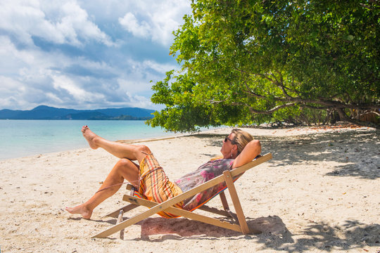 Woman reclining in deckchair on beach, Koh Rang Yai, Thailand, Asia
